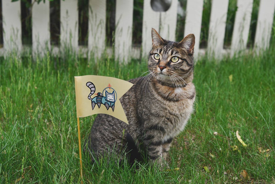 A cat next to a sticker of an astronaut space-cat