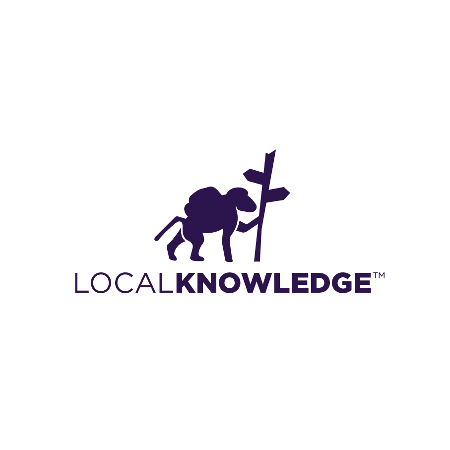 silhouette of a baboon with a backpack standing by a signpole