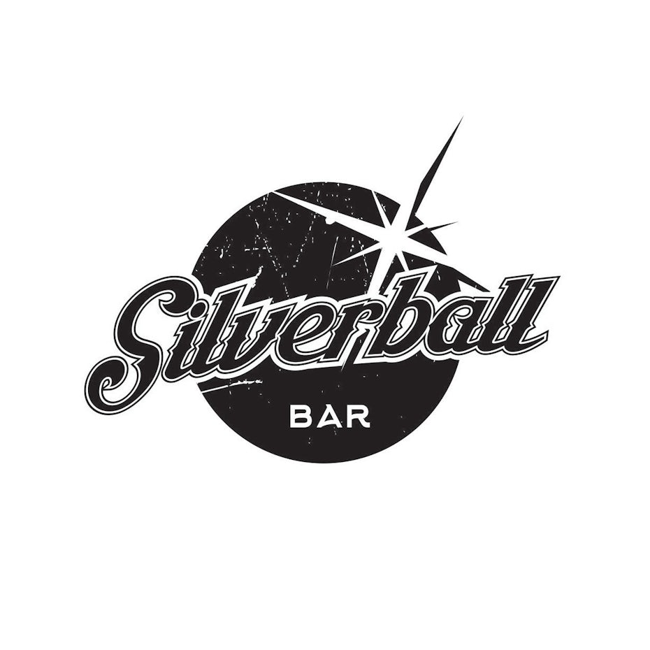 round distressed logo with the wordmark across a depiction of a pinball
