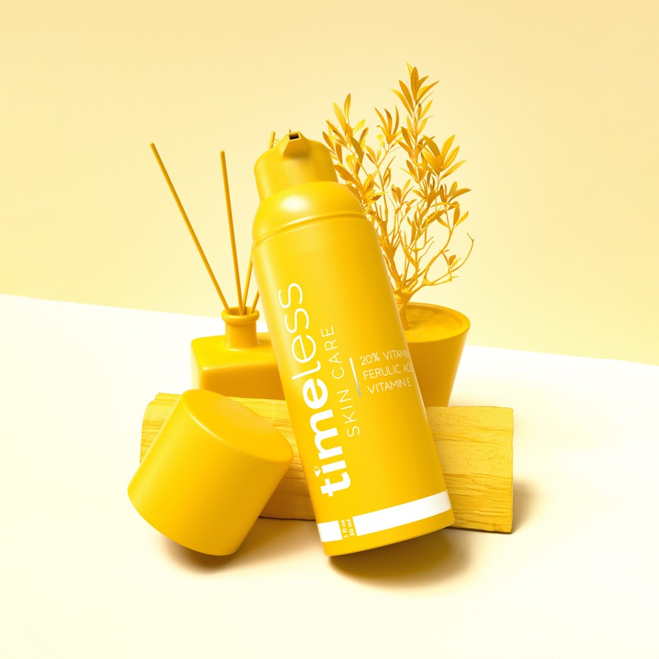 solid color packaging design trend: mockup of a yellow cosmetics bottle laid against a plant, a diffuser and a block of wood