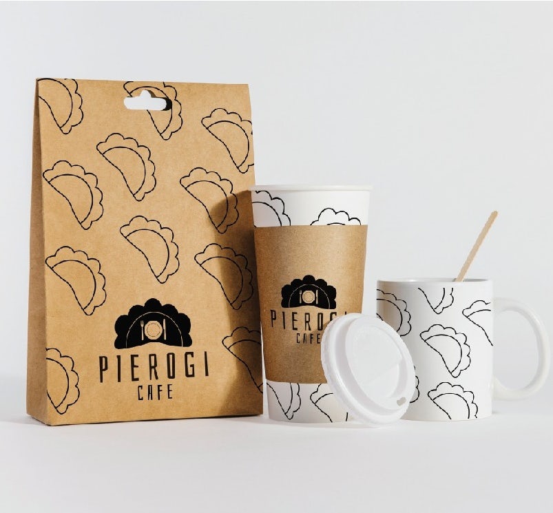 brown paper bag with line illustrations of pierogies alongside a paper coffee cup and a mug