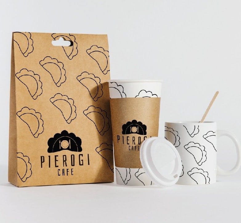 brown paper bag with line illustrations of pierogies alongside a paper coffee cup and a mug