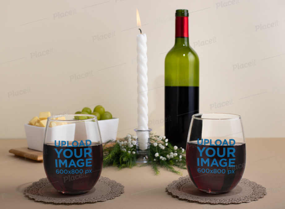 two stemless wine glasses on a table with a wine glass and a candle