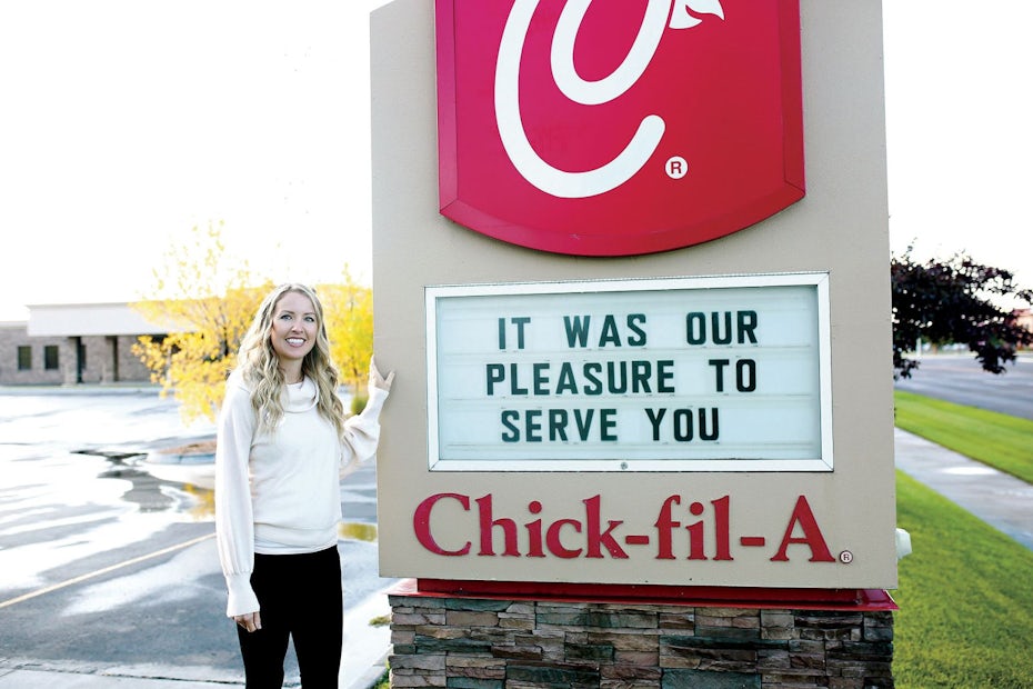 photo of a woman standing beside a Chick Fil A sign