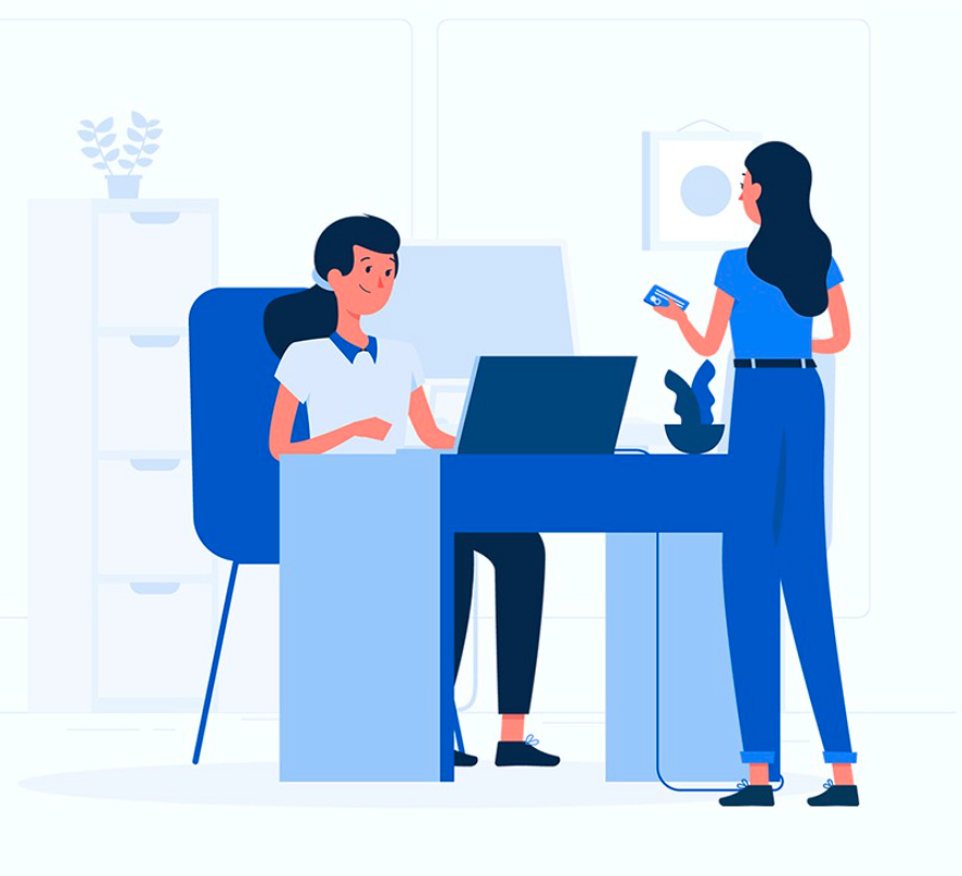 a woman sitting at a desk while a woman standing hands her a credit card