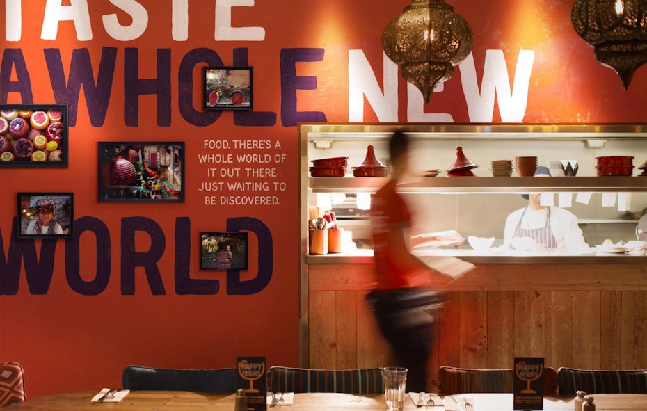 an interior view of a kitchen counter backdropped against an orange wall filled with photographs