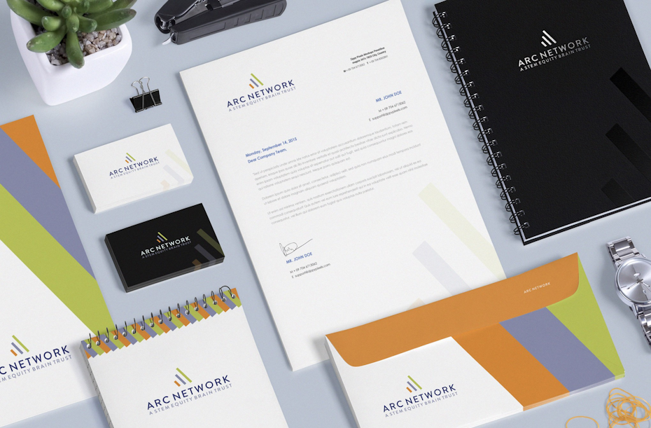 a table full of business cards and office stationeries, like a black notebook, an envelope with orange, blue, and green stripes, and a company letterhead