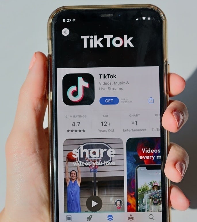 eine Person, die ein Telefon im App Store hält und TikTok herunterlädt