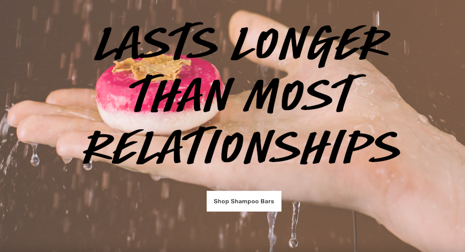 Hand holding bar of shampoo by cosmetics brand Lush, with advertising slogan scrawled across.