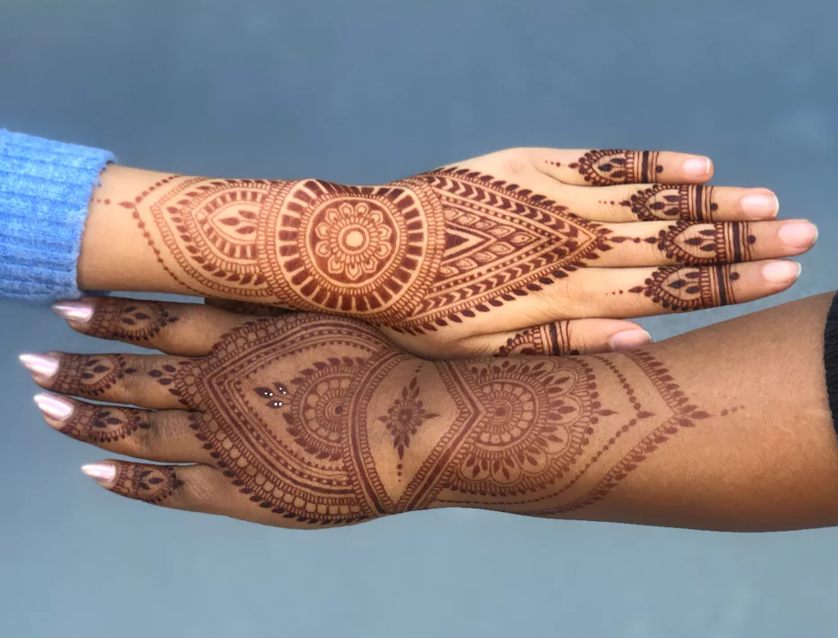 Photo of two hands side by side with henna body art designs