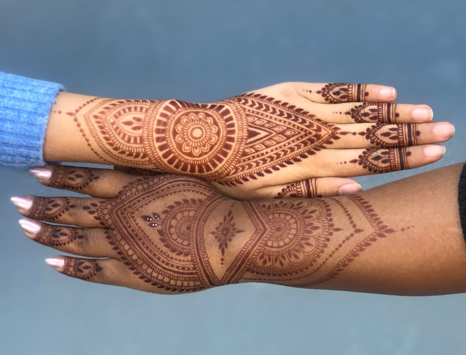 Photo of two hands side by side with henna body art designs