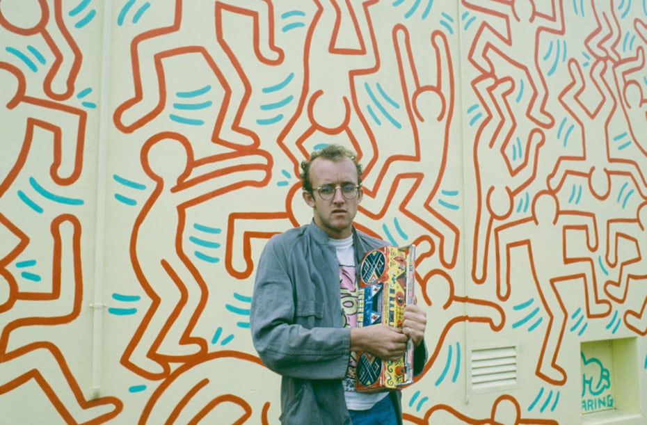 Photograph of Keith Haring in front of a mural of his artwork
